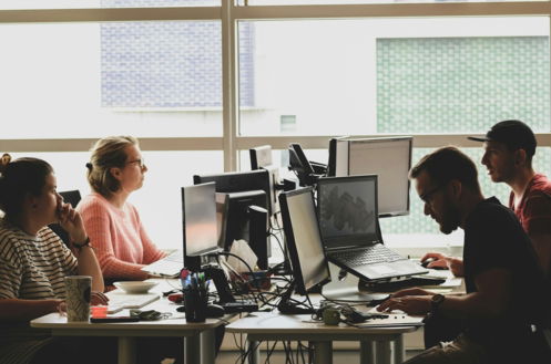 woman in pink shirt sitting in front of black laptop computer